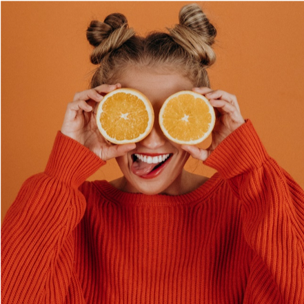 Woman holding oranges over her eyes
