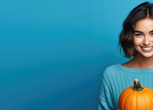 Brunette woman holding a pumpkin on a bright blue background