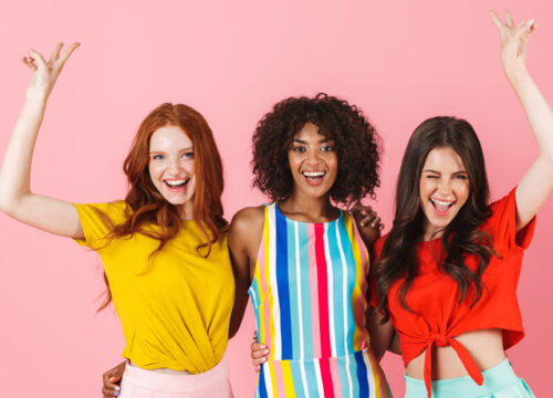 Three diverse women looking happy on a pink background