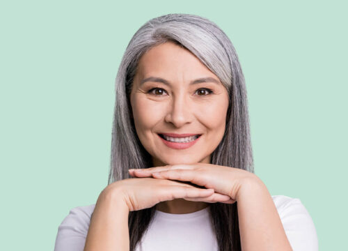 Woman with grey hair resting her chin on her hands